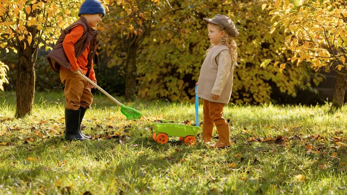 Children raking autumn leaves under golden trees
